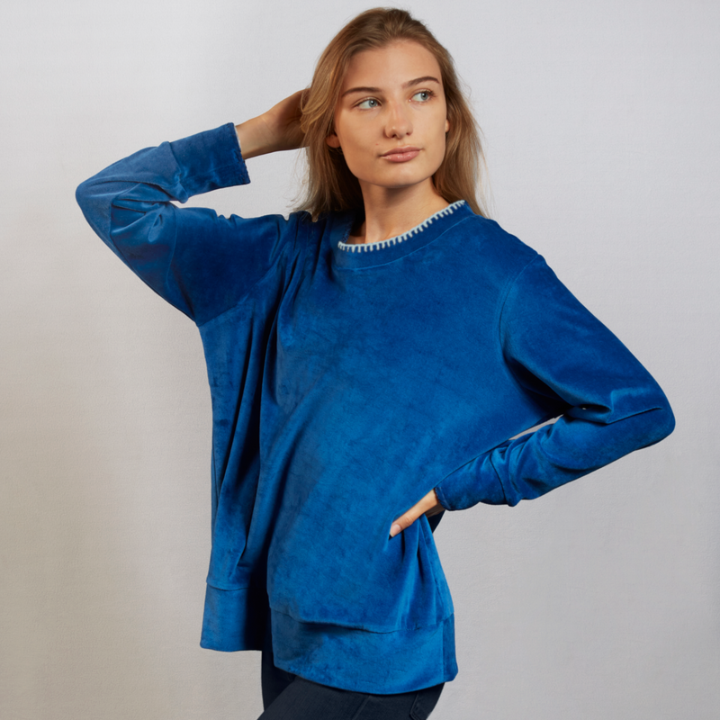 Woman wearing a blue velour nautical themed top with a white background