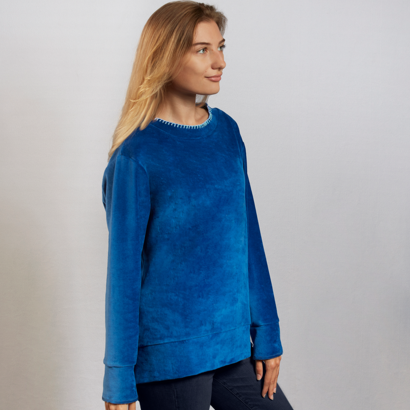 Woman wearing a blue nautical themed velour top with a white background