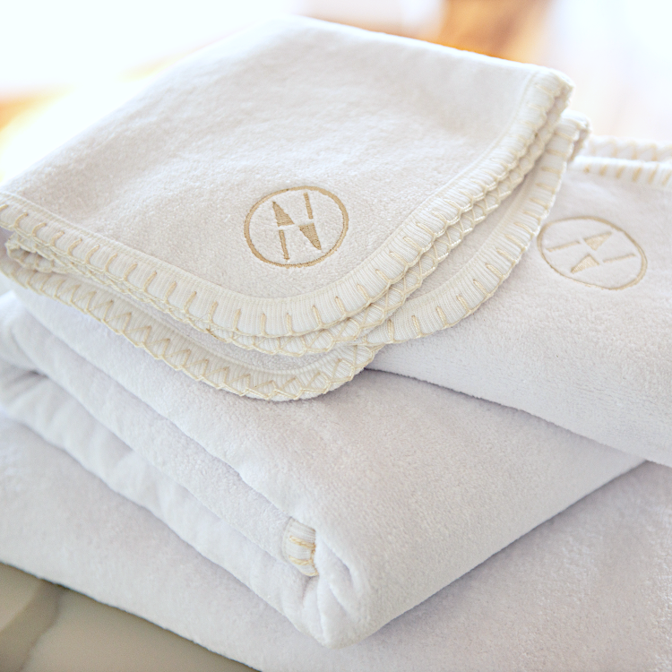 White nautical themed washcloths resting on top of a stack of white bath towels.