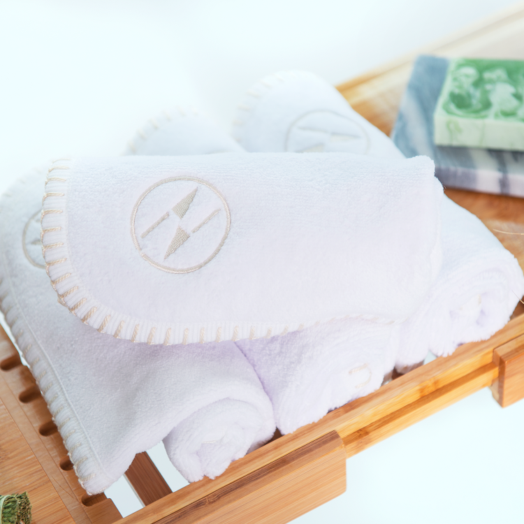 A white nautical themed washcloth and hand towel set resting on a wooden tray