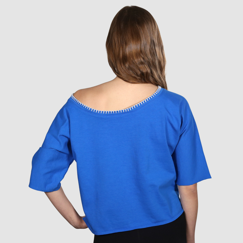 Woman with her back to camera wearing a blue wide neck nautical themed T Shirt on a white background