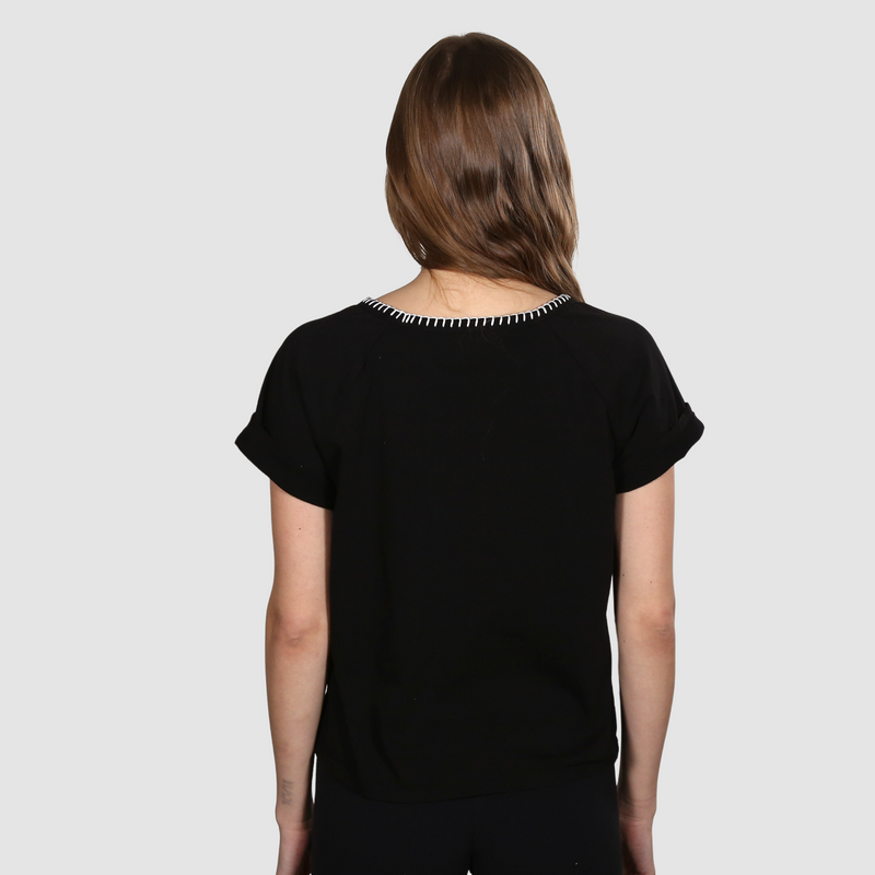 Woman with her back to the camera wearing a black nautical themed crew neck T Shirt on a white background