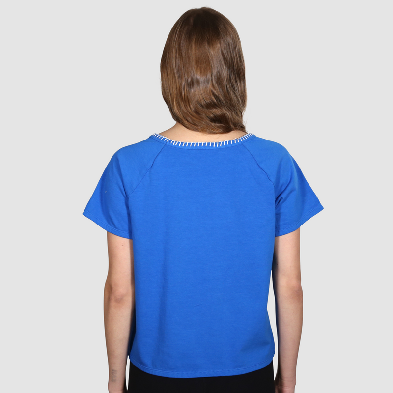 Woman with her back to the camera wearing a blue nautical themed crew neck T Shirt on a white background