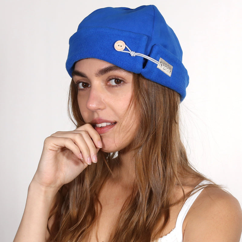 Woman wearing a blue nautical themed beanie on a white background