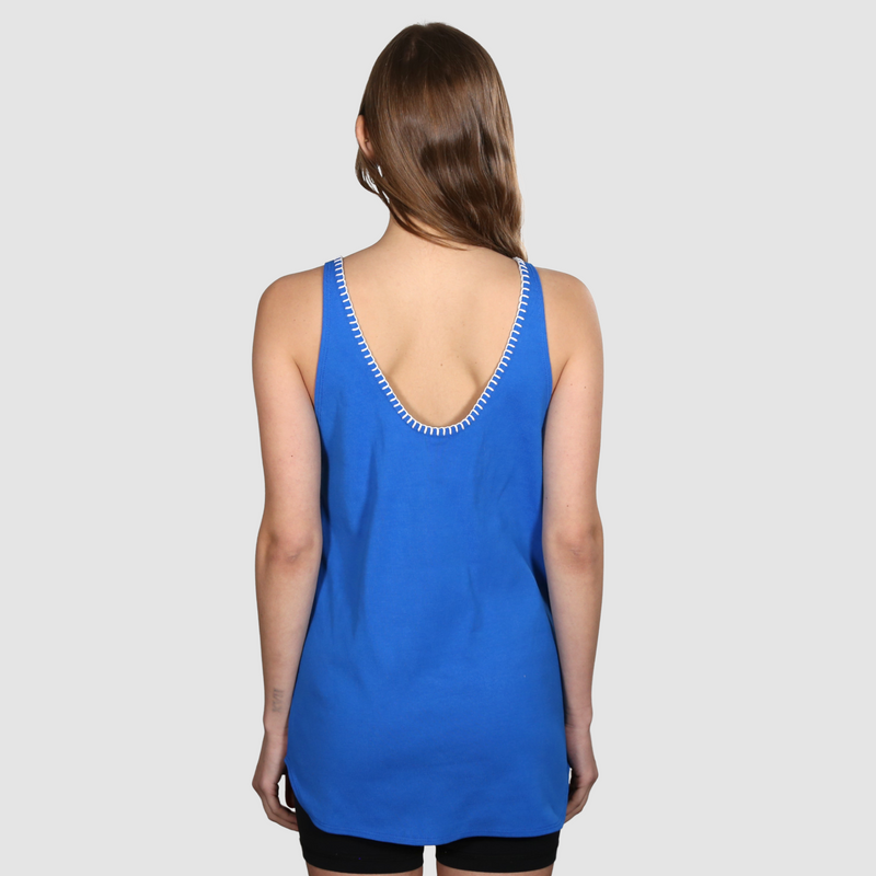 Woman facing away from the camera wearing a blue nautical themed tank top on a white background