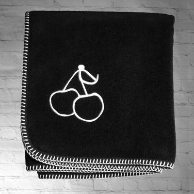 A black nautical themed towel with white stitching and an image of two cherries embroidered on to the towel.