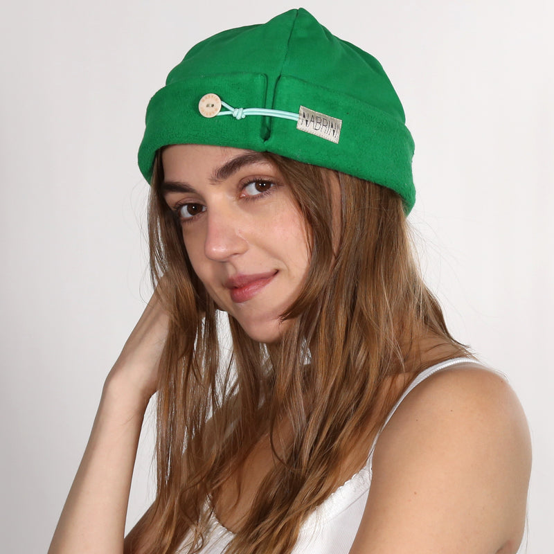 Woman wearing a nautical themed green beanie on a white background