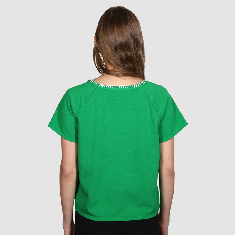 Woman with her back to the camera wearing a green nautical themed crew neck T Shirt on a white background