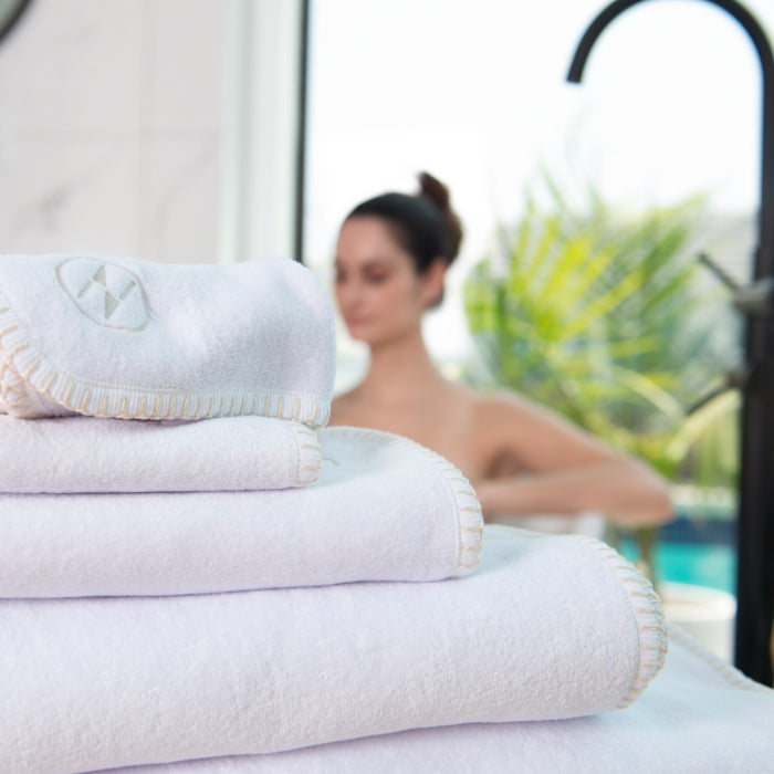 A stack of white nautical themed Bath, Hand, and Wash towels with a female model blurry in the background