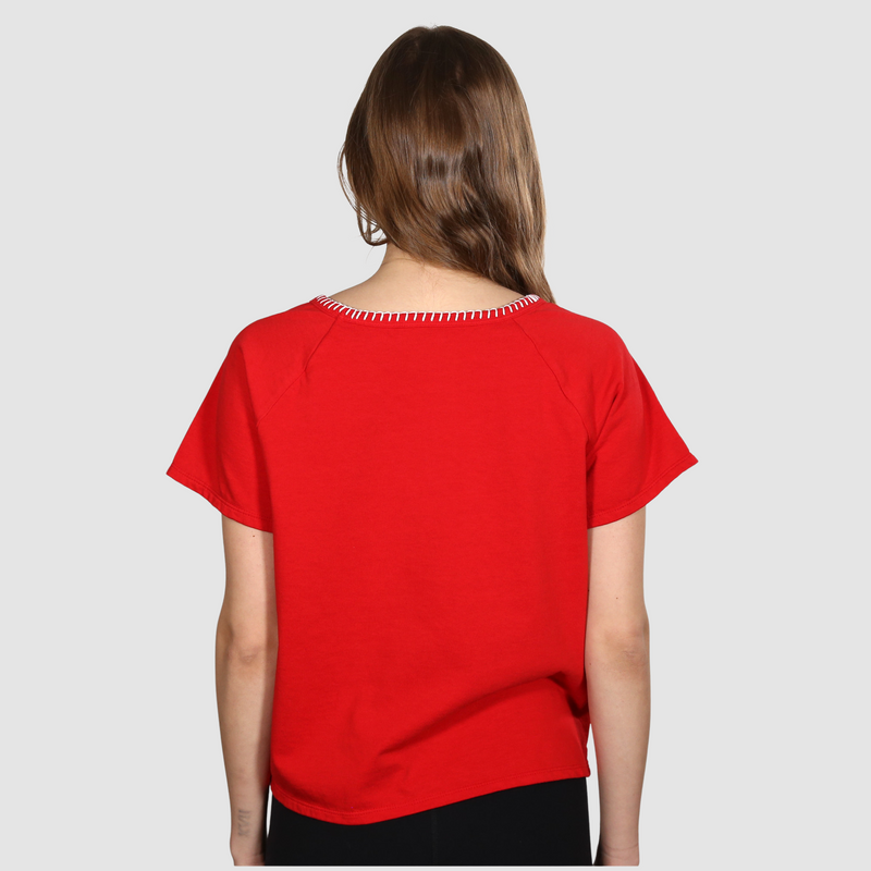 Woman with her back to the camera wearing a red nautical themed crew neck T Shirt on a white background