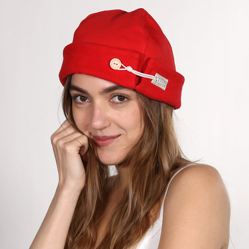 Woman wearing a red nautical themed beanie on a white background