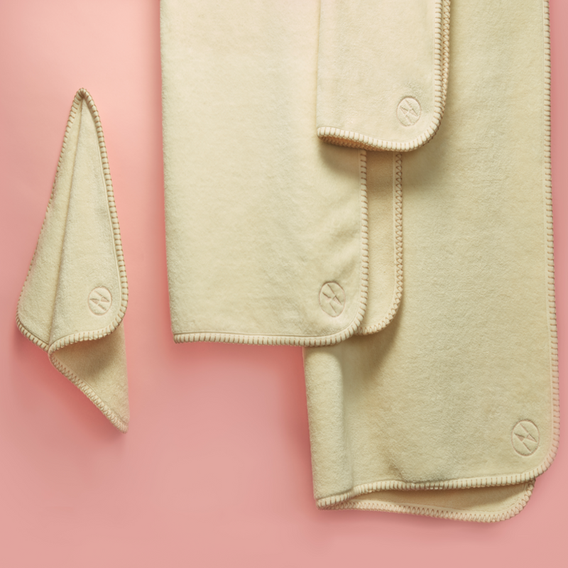 4 Champagne colored nautical themed towels hanging on a pink wall.