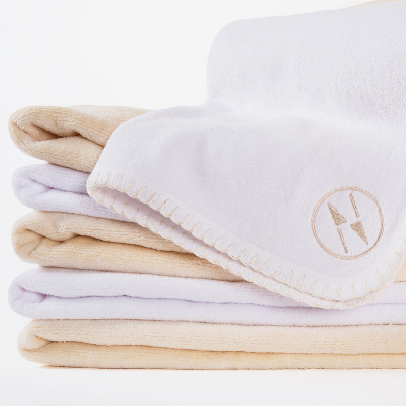 A stack of alternating colored white and Champagne colored nautical themed bath towels on a white background