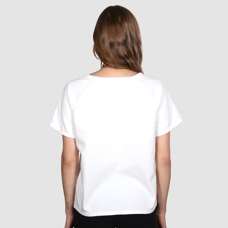 Woman with her back to the camera wearing a white nautical themed crew neck T Shirt on a white backgound