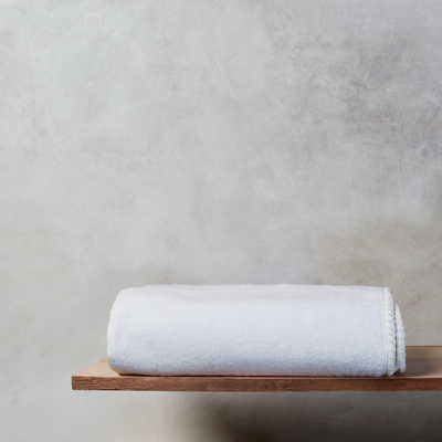 White nautical themed bath towel resting on a wooden shelf with a grey background
