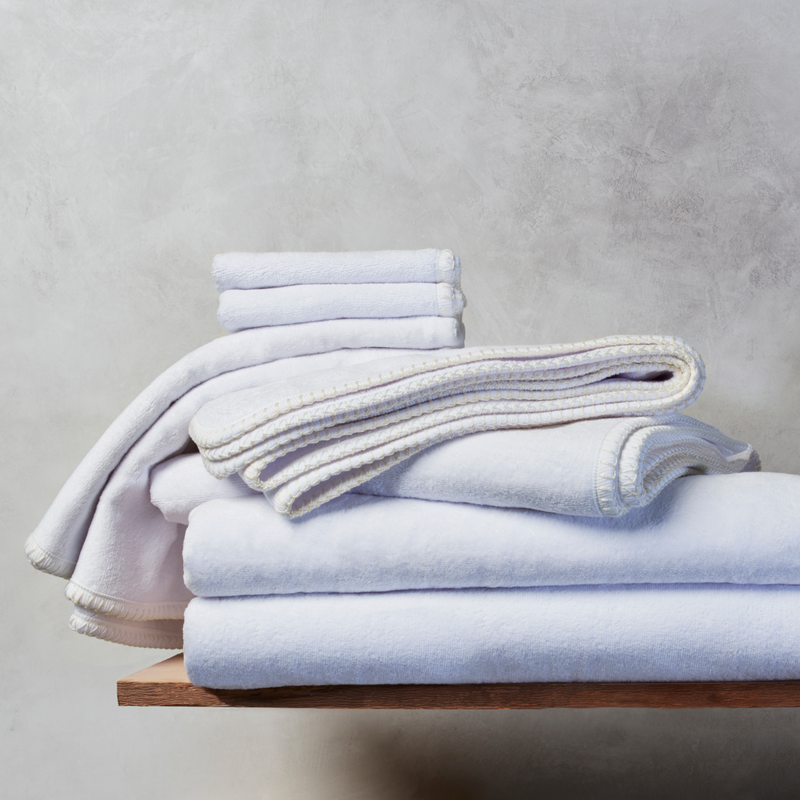 A stack of nautical themed towels on a wooden plank against a grey background