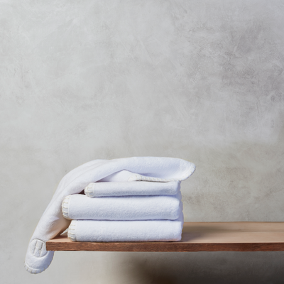 Two nautical themed Handtowels and two wash cloths folded and resting on a wooden shelf on a grey background