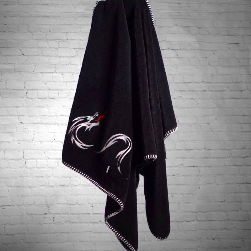 A nautical themed black towel hanging with white edge stitch and a dragon embroidered on it.