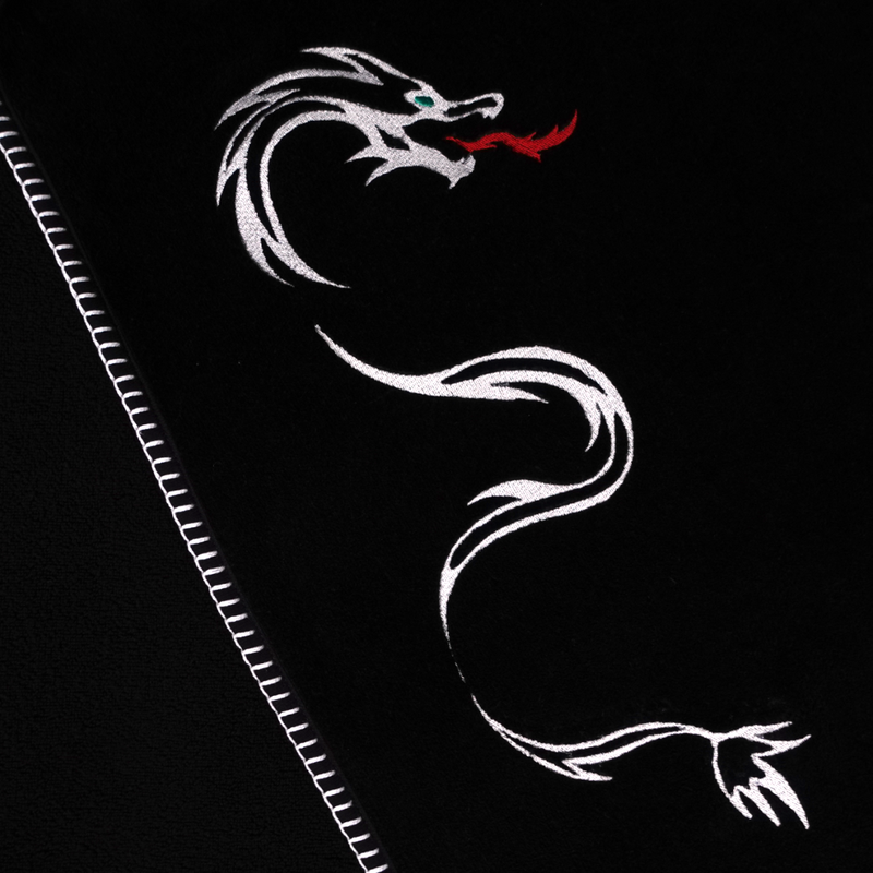 A nautical themed black towel with white edge stitching and a large embroidery of a dragon with red flames comming out of its mouth